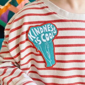 Elephant shaped embroidered kids badge/patch with the words/sloagn 'kindness is cool' irons on and then sew into place. Sewn onto children's T-shirt. 